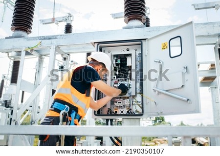 Adult electrical engineer inspect the electrical systems at the equipment control cabinet. Installation of modern electrical station Royalty-Free Stock Photo #2190350107
