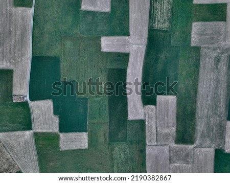 Aerial texture in landscape mode of mountain agricultural fields, green pastures and harvests.