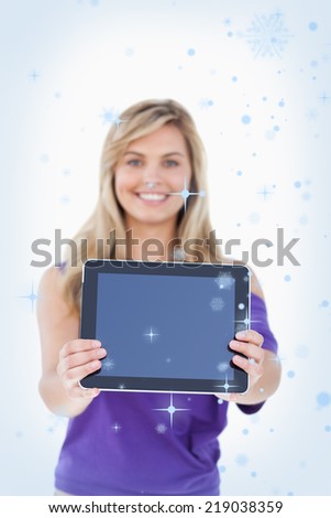 Composite image of Tablet computer being held by a blonde woman with snow falling