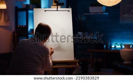 Old woman with creative skills drawing professional artwork with vase inspiration and artistic equipment. Using tools and pencils to create art masterpiece on white canvas, draw sketch. Royalty-Free Stock Photo #2190383829