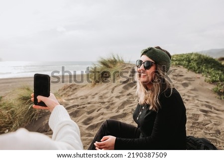 Two girls relaxing, sitting and taking theirself photos on the beach. Overcoming depression