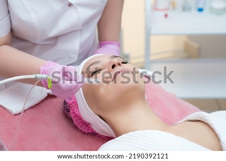 Woman getting face peeling procedure in a beauty SPA salon. Rejuvenating facial gas liquid treatment.  Hydro air skin cleansing operation. Close up, selective focus. Royalty-Free Stock Photo #2190392121