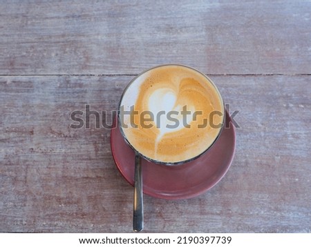 Hot latte art coffee in cup on wooden table, Fresh morning coffee with delicious milk foam. Top view, flat lay.