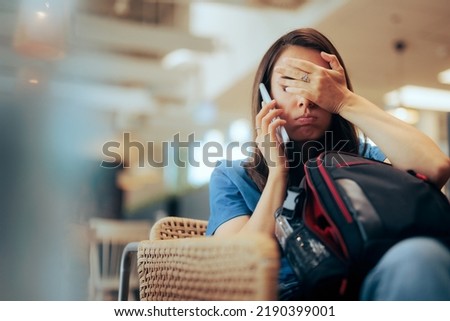 Unhappy Woman Talking on the Phone Waiting in an Airport 
Stressed traveler speaking on her cellphone feeling overwhelmed Royalty-Free Stock Photo #2190399001