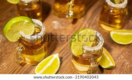 tequila shots served in jars with salt and lemon on wooden table with dark background and luxury bottle