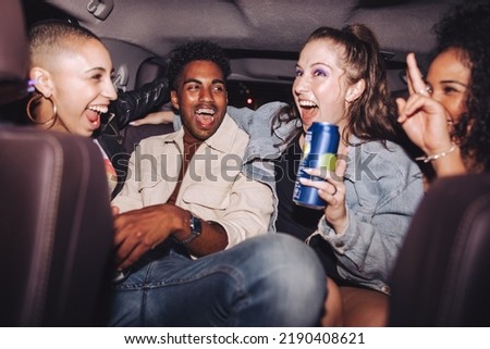 Cheerful friends having fun in the back seat of a car. Group of diverse young people laughing together while sitting in a cab. Four happy friends having a good time on their way home after a party. Royalty-Free Stock Photo #2190408621