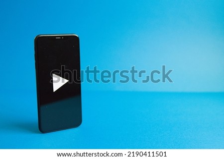A smartphone with a play mark and a photo on the left with a blue background