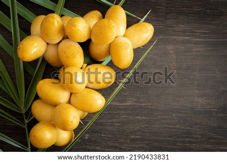 Fresh Date Palm with leaves on black wood , Yellow Date Palm on wood, Date Palm Fresh Royalty-Free Stock Photo #2190433831