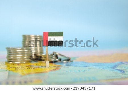 Selective focus of UAE flag in blurry world map with coins. UAE economy and wealth concept.