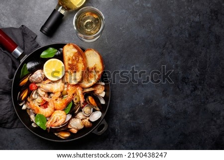 Mixed grilled seafood. Various roasted shrimps, mussels and shellfish in frying pan and white wine. Top view flat lay with copy space Royalty-Free Stock Photo #2190438247