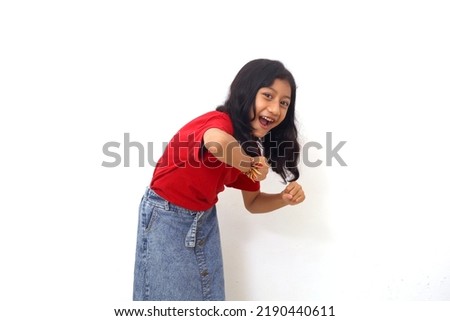 Cheerful asian little girl standing while dancing. Isolated on white background