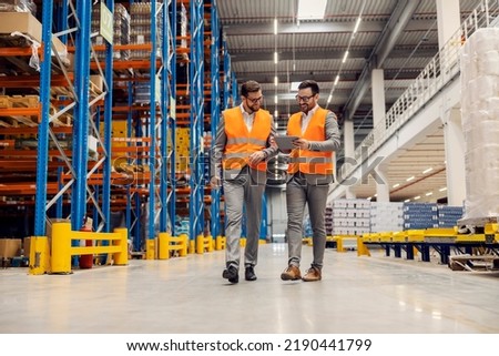 Businesspeople dispatching warehouse and smiling at the tablet. Royalty-Free Stock Photo #2190441799