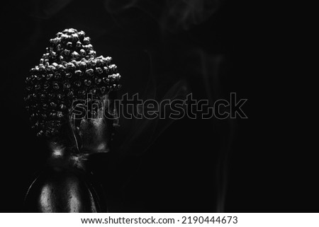 Buddha face from right side, with incense smoke. dark background