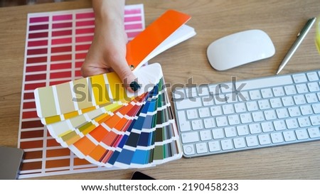 Top view of female interior designer showing fan of colourful samples. Woman searching proper colour for promotion. Design and art concept