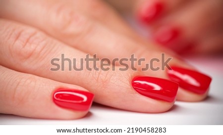 Close-up of female hand with stylish bright red glossy manicure. Beautiful female fingernails with gel polish. Beauty salon and body care concept Royalty-Free Stock Photo #2190458283
