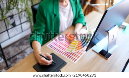 Top view of woman interior designer working with fan of colourful samples in office. Female searching proper colour for promotion. Design and art concept