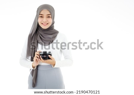 Young beautiful young Asian Islamic businesswoman holding a vintage camera. Muslim women concept with hobbies and art photography. Royalty-Free Stock Photo #2190470121