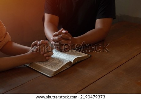 Two people are praying together over holy bible on wooden table  Royalty-Free Stock Photo #2190479373