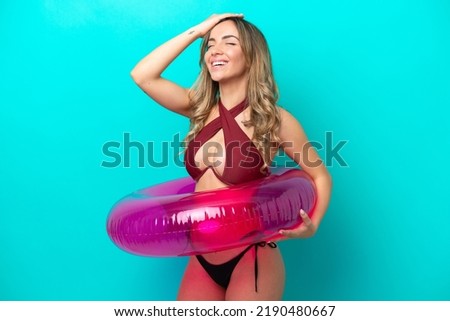 Woman in swimsuit holding floater isolated on blue background has realized something and intending the solution