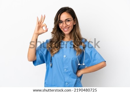 Young surgeon doctor woman over isolated white wall showing ok sign with fingers