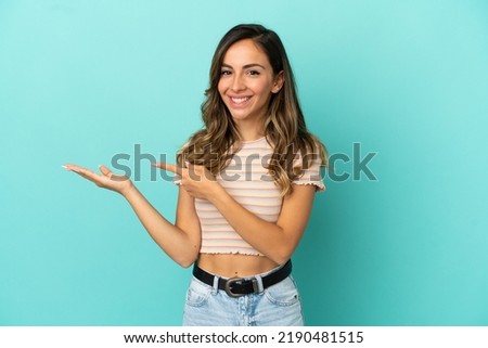 Young woman over isolated blue background holding copyspace imaginary on the palm to insert an ad