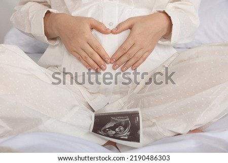 Pregnant woman with ultrasound scan on bed, closeup