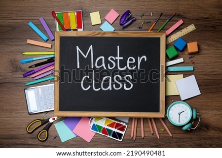 Blackboard with words Master Class surrounded by different stationery on wooden table, flat lay