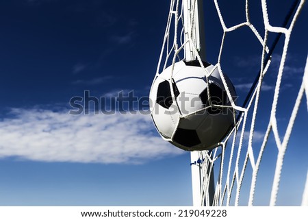 Soccer football in Goal net with sky field. Dark contrast