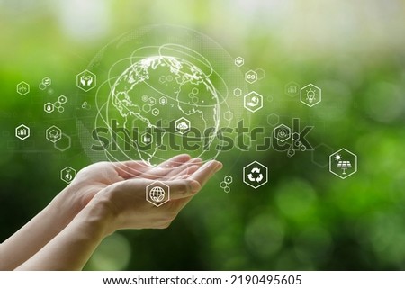Sustainable development goal (SDGs) concept. Hands holding Global communication network with Environment icon on a green background. Green technology and Environmental technology. Royalty-Free Stock Photo #2190495605