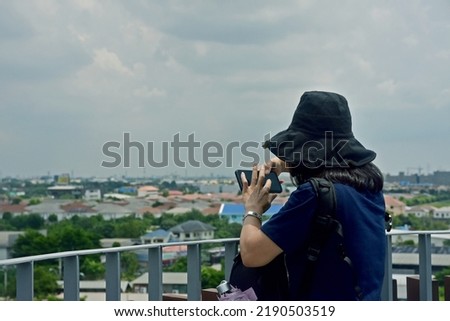 Attractive young girl wearing casual outfit spending time outdoors at the park, taking pictures with mobile phone