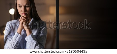 Praying young woman at home in evening. Banner for design