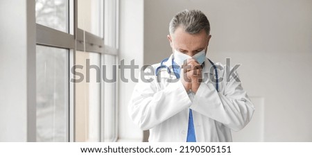 Praying mature doctor in clinic
