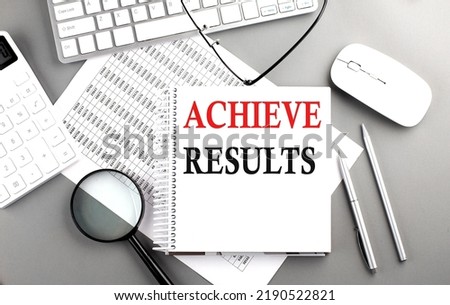 ACHIEVE RESULTS text on a notepad on chart with keyboard and calculator on grey background
