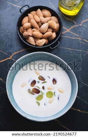 Bowl of ajoblanco or spanish white gazpacho served with grapes, high angle view on a dark-olive marble background, vertical shot Royalty-Free Stock Photo #2190524677