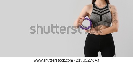 Sporty woman holding foam roller on grey background with space for text