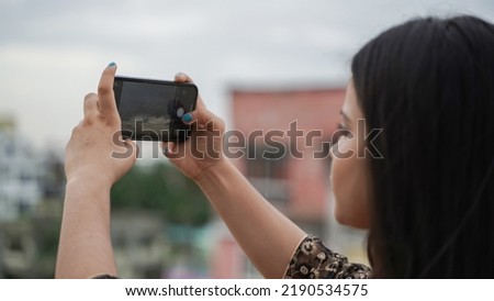 Beautiful Indian woman taking photo with her mobile phone camera, young female Asian photographer