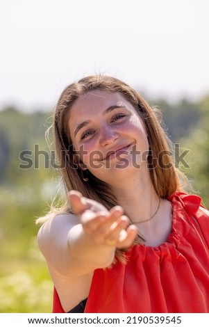 Portrait of a happy young woman reaching out to the hand of her boyfriend or partner while walking by in a countryside rural area. Couple enjoying a hike in nature. High quality photo