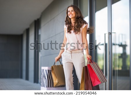 Young woman with shopping bags walking out from shop Royalty-Free Stock Photo #219054046