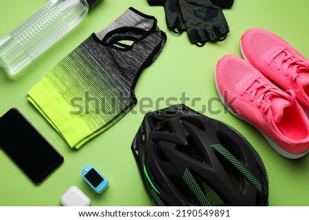 Flat lay composition with different cycling accessories and clothes on green background