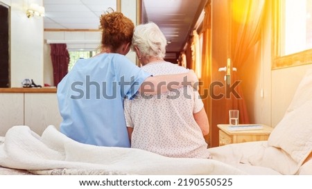 Nurse in hospice hugs elderly woman on bed for comfort while grieving Royalty-Free Stock Photo #2190550525