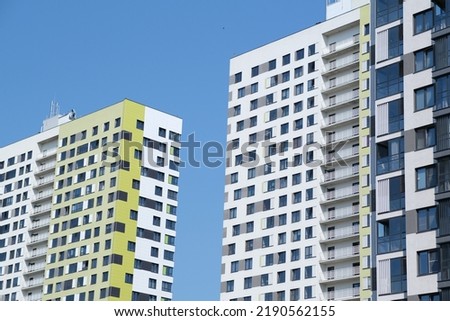Facade of modern building in city. From below of contemporary high rise buildings with glass mirrored windows against cloudless blue sky