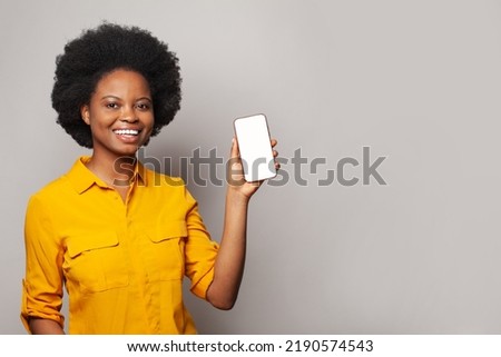 Happy black woman showing empty blank screen display smart phone against white studio wall background