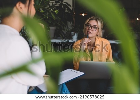 Caucasian female freelancer in spectacles for provide vision correction communicate with business colleague about laptop networking for web enterprise, skilled women with netbook cooperate together Royalty-Free Stock Photo #2190578025