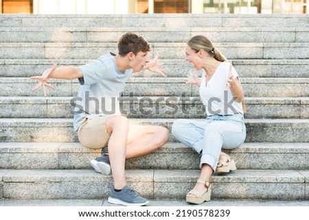 Teenager couple discussion. Toxic relationship concept. Boy and girl shouting sitting on stairs. Royalty-Free Stock Photo #2190578239