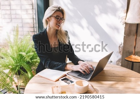 Happy entrepreneur in eyewear using laptop technology for browsing journalistic website in social networks, skilled woman in smart casual clothes connecting to 4g wireless on netbook - freelance job
