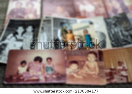 A close-up, blurry, out-of-focus background of old family photos in black and white and sepia lined up for the emotion of nostalgic memories of the past.