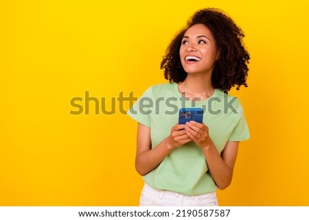 Photo of dreamy shiny lady wear green t-shirt typing modern gadget looking empty space isolated yellow color background