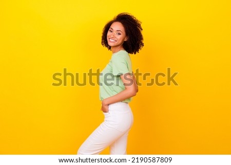 Photo of cheerful positive girl dressed green t-shirt smiling arms hands pockets isolated yellow color background