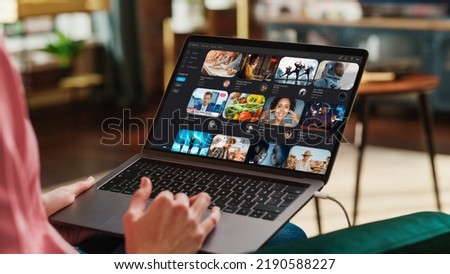Young Beautiful Woman Using Laptop to Watch Videos on Online Streaming Service. Creative Female Checking Social Media, Browsing Internet, Consuming Content. Urban City View from Big Window. Royalty-Free Stock Photo #2190588227