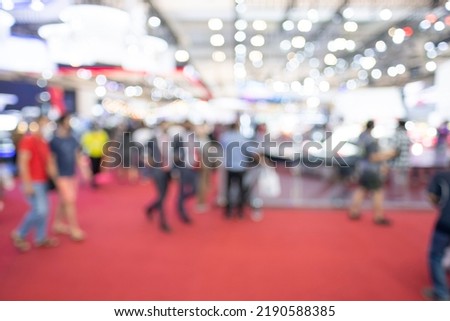 Blurry crowd visitors walking in an exhibition event hall. Bokeh background of trade show business, world or international expo showcase, tech fair, with exhibitor trade show booth displaying product. Royalty-Free Stock Photo #2190588385